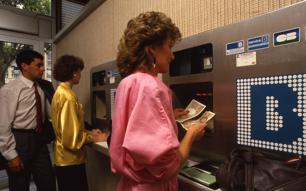 Agence de la BNP located Avenue des Champs Elysées: Clients withdraw cash from one of its ATMs, 1986.